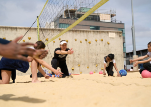 Volleyball coach instructing children on the sand court at Marlborough Sports Garden
